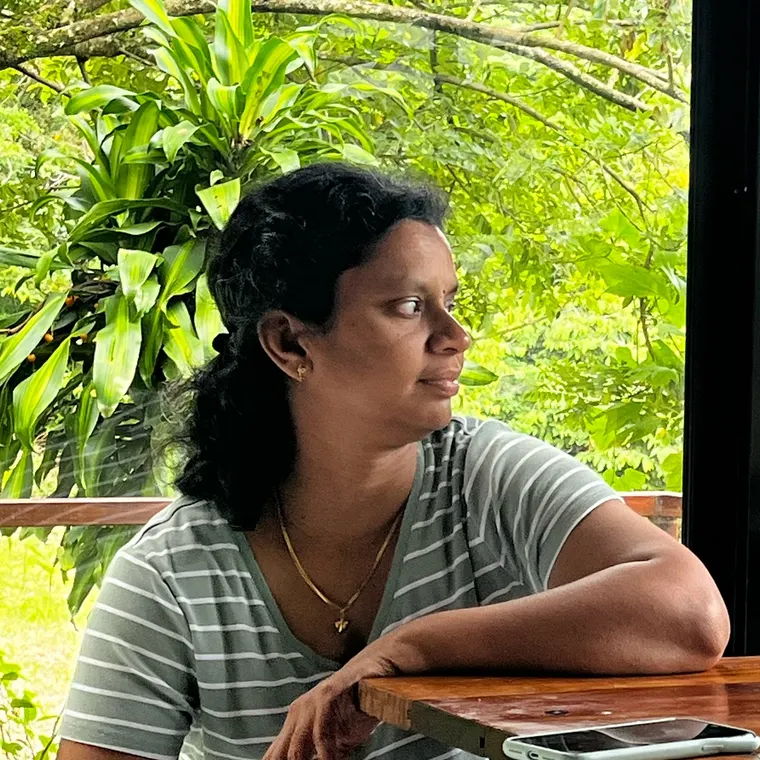 Amma at a table by a window, looking out at the trees